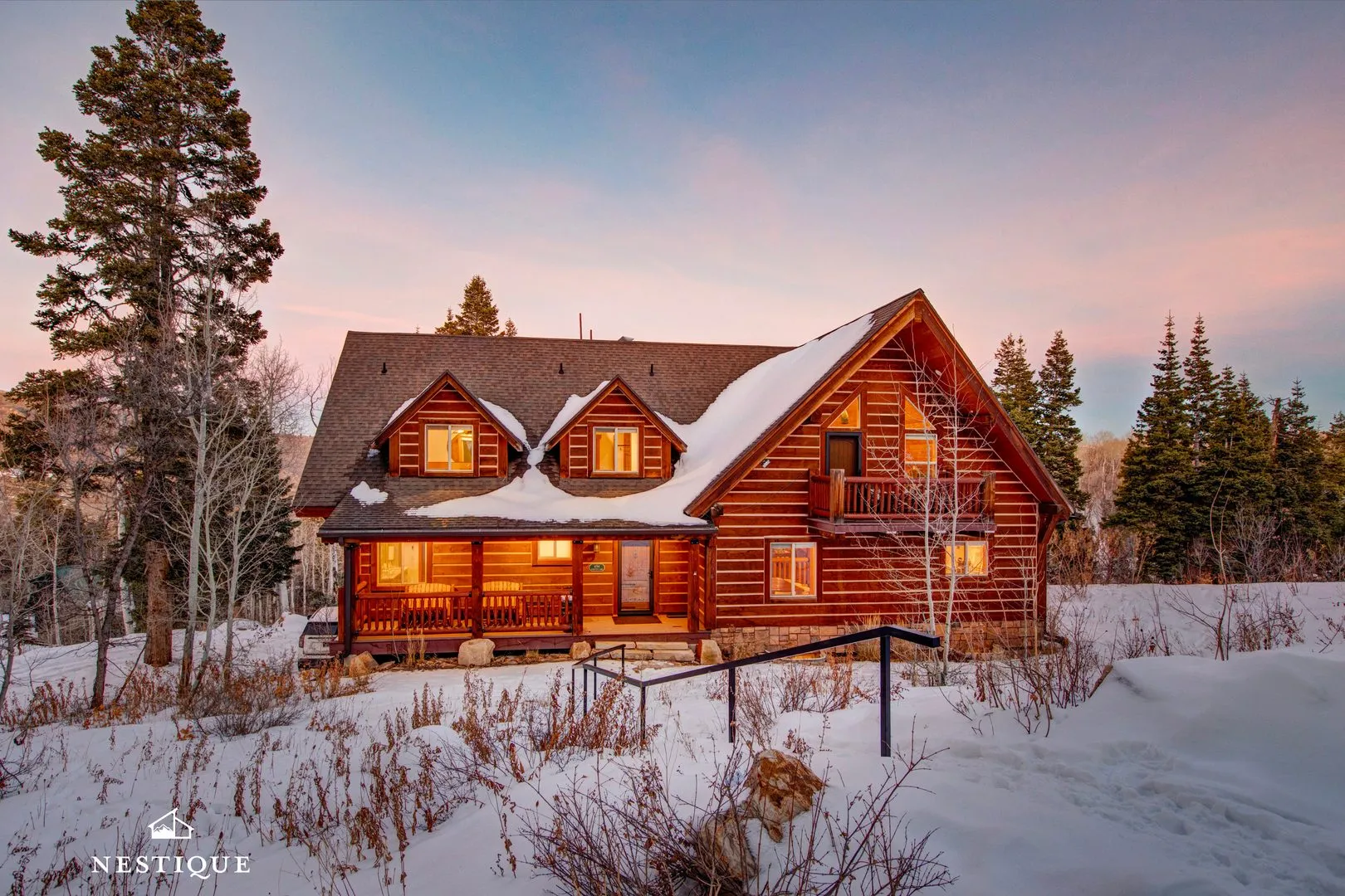 Unforgotten Utopia, a log home in Tollgate Canyon, glowing at dusk after fresh snow