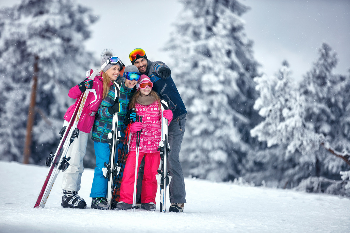 Family with skis smiling in falling snow on a Park City ski day